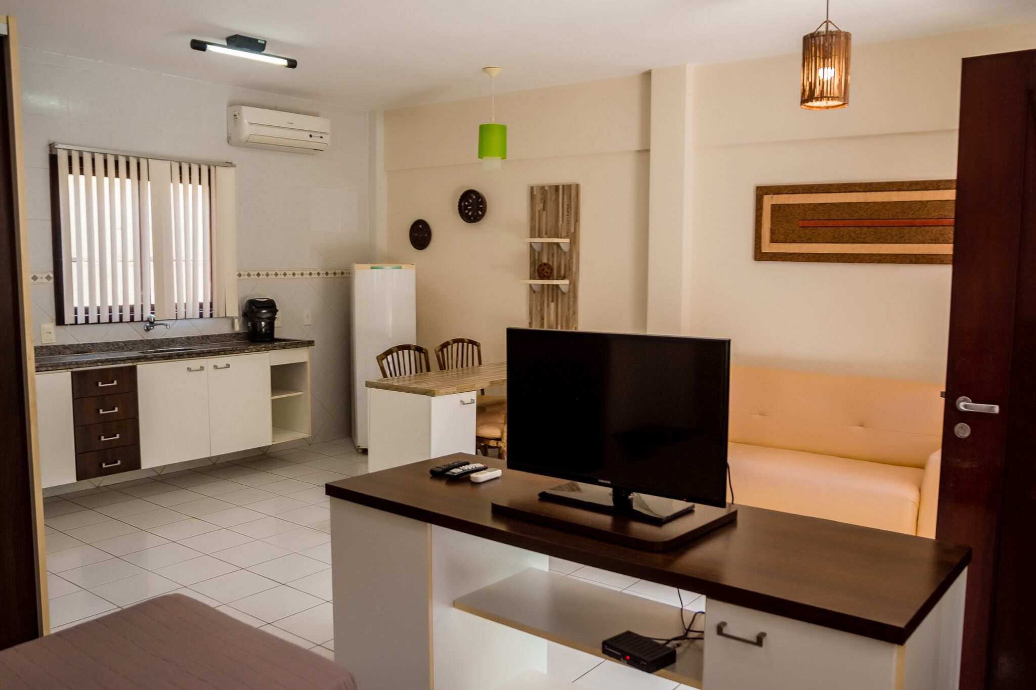 A modern kitchen with white cabinets, a built-in stove, and a dining area with a white table and chairs.