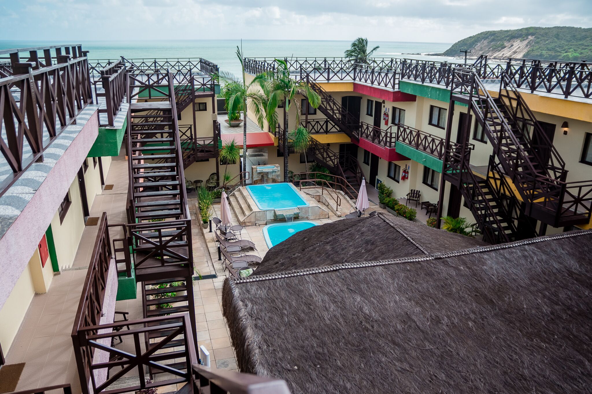 Um resort com vários edifícios, piscina e vista para o oceano.