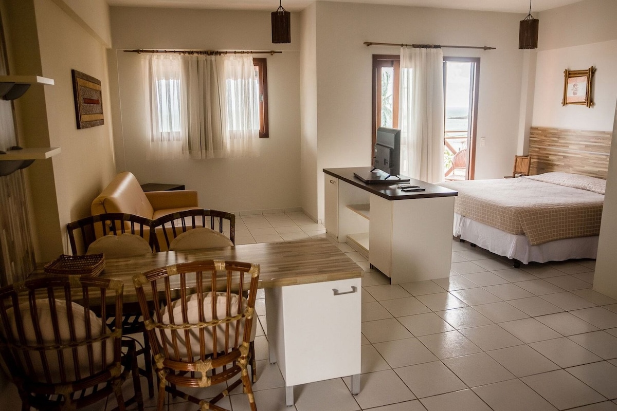 Une pièce comprenant un lit, un bureau avec un ordinateur, une chaise et une table à manger avec des chaises.
