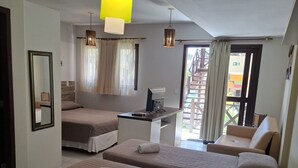 Habitación de hotel con cuatro camas, un escritorio con computadora, un espejo y vistas al exterior.
