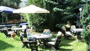 Un espace extérieur aménagé avec des tables et des chaises, entouré de verdure.