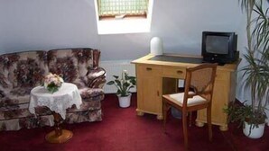 Une pièce comprenant un canapé, un bureau avec une chaise, une télévision et une fenêtre.
