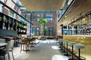 A modern interior with a bar area, seating, and a large window overlooking a brick building. - Conferentiehotel Kontakt der Kontinenten (Soesterberg)
