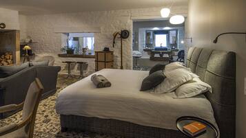 A hotel room with a large bed, a chair, a small table, a mirror, and a view of the outside.