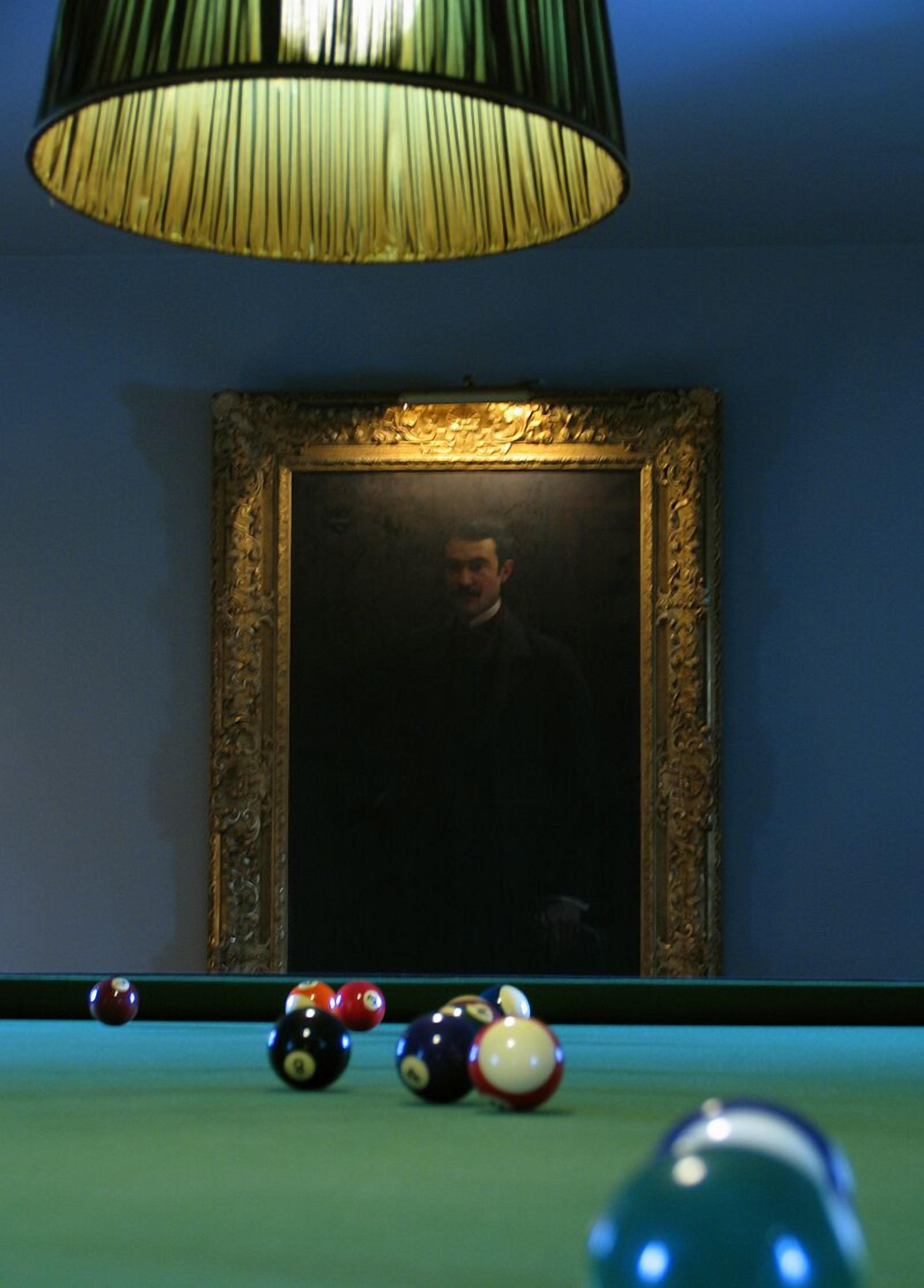 Una mesa de billar con bolas y un retrato enmarcado al fondo.
