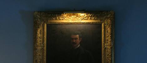 A billiards table with balls and a framed portrait in the background.
