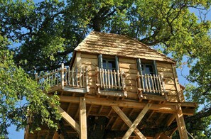 A wooden treehouse with a balcony, built on a sturdy wooden structure. - Château de Labro (Onet-le-Chateau)