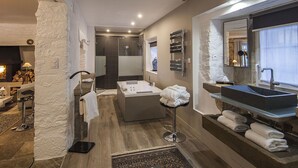 A modern bathroom with a large bathtub, a glass-enclosed shower, and a vanity with a large mirror.