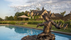 A statue by a pool with a castle in the background.
