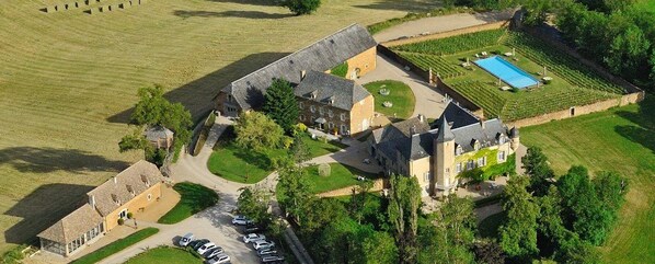 An aerial view of a large estate with multiple buildings, a swimming pool, and a vineyard.