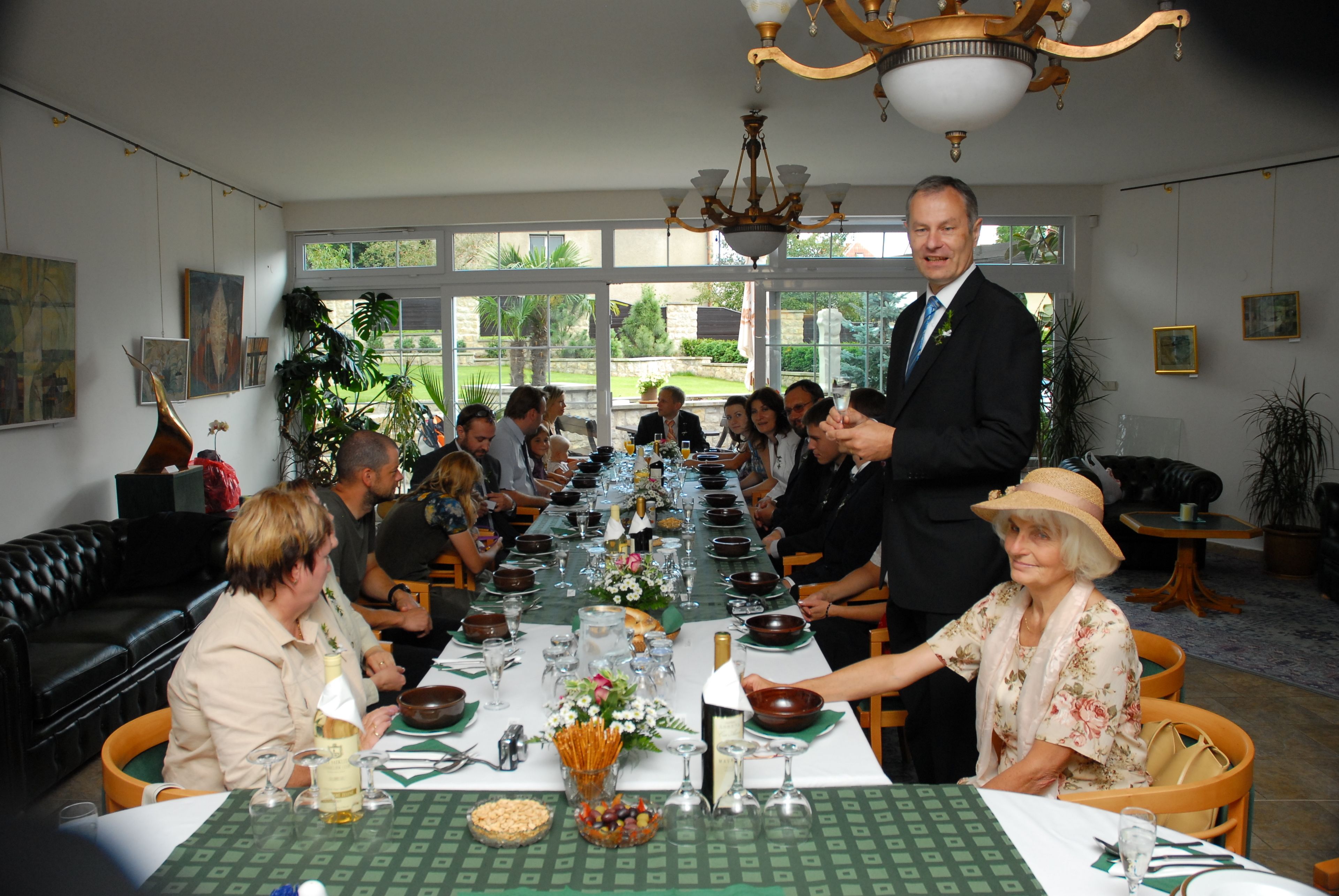 Une salle à manger élégante, avec une longue table dressée pour un repas, entourée d’invités.