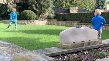 Sit and unwind on a serene stone bench amidst lush greenery and mature trees.
