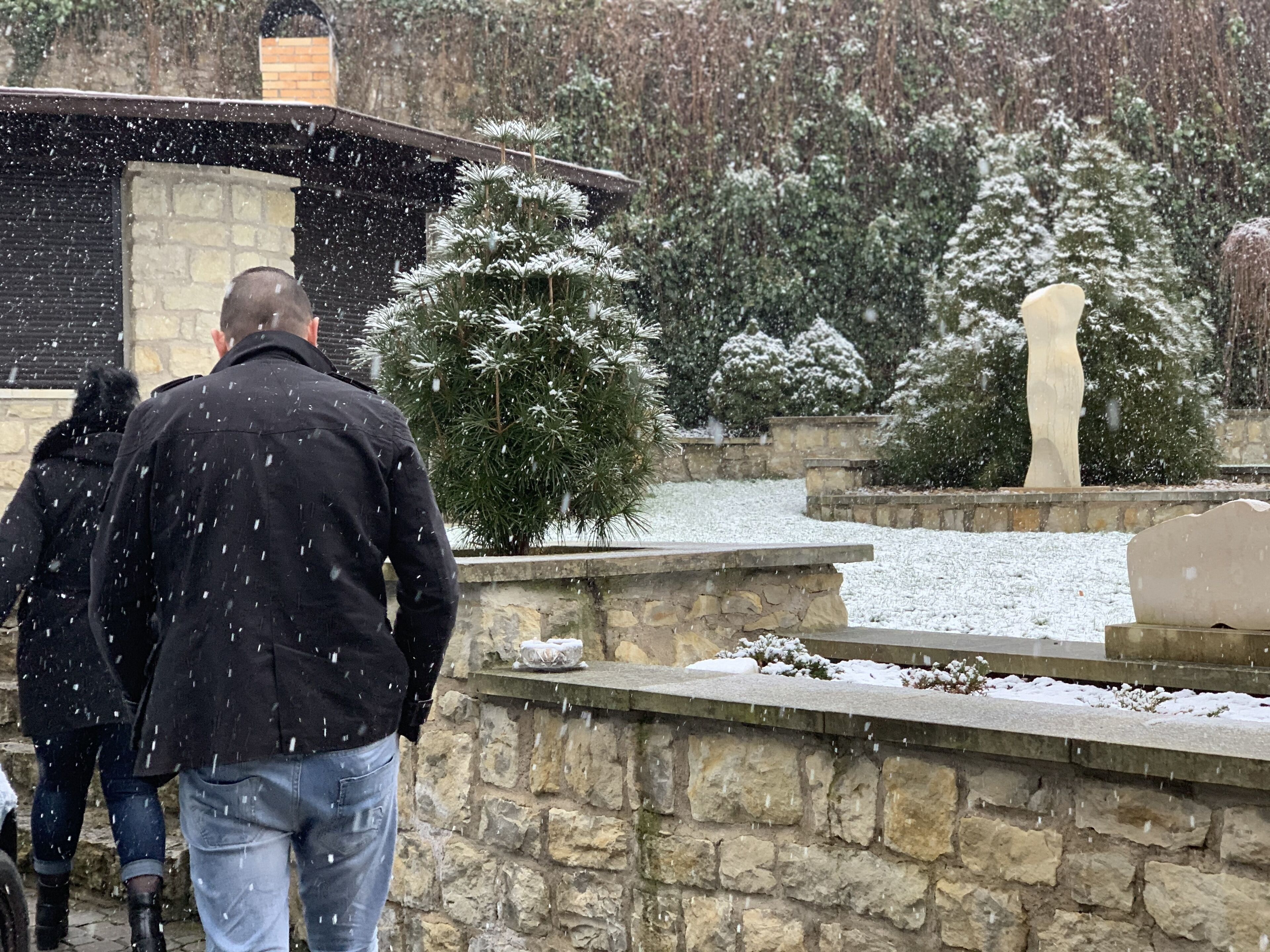 A stone pathway leading to a building with a stone facade and a snow-covered landscape.