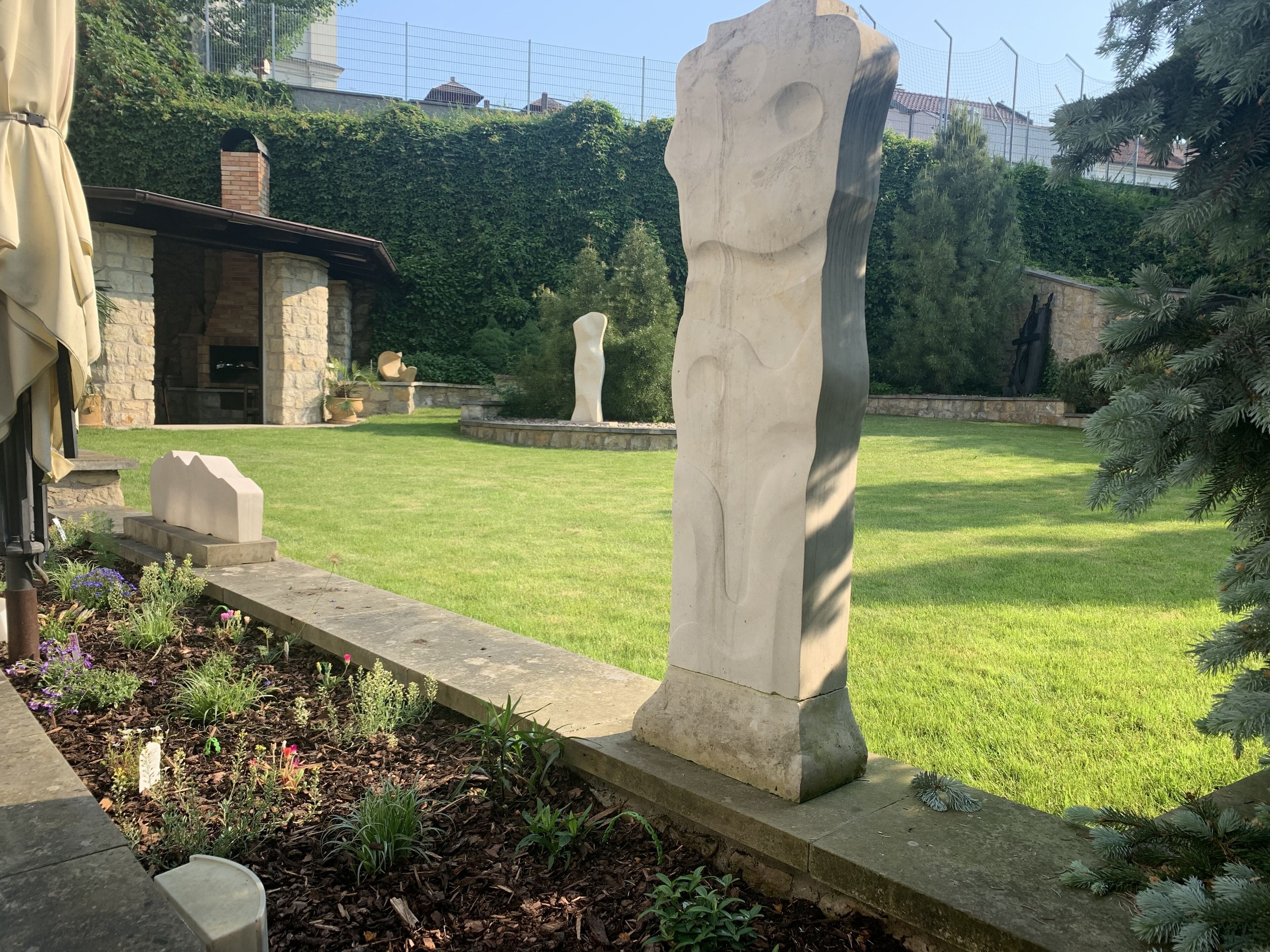 A garden with a stone sculpture, a stone bench, and a stone wall.