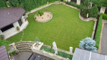 A courtyard with a lawn, stone walls, and potted plants.