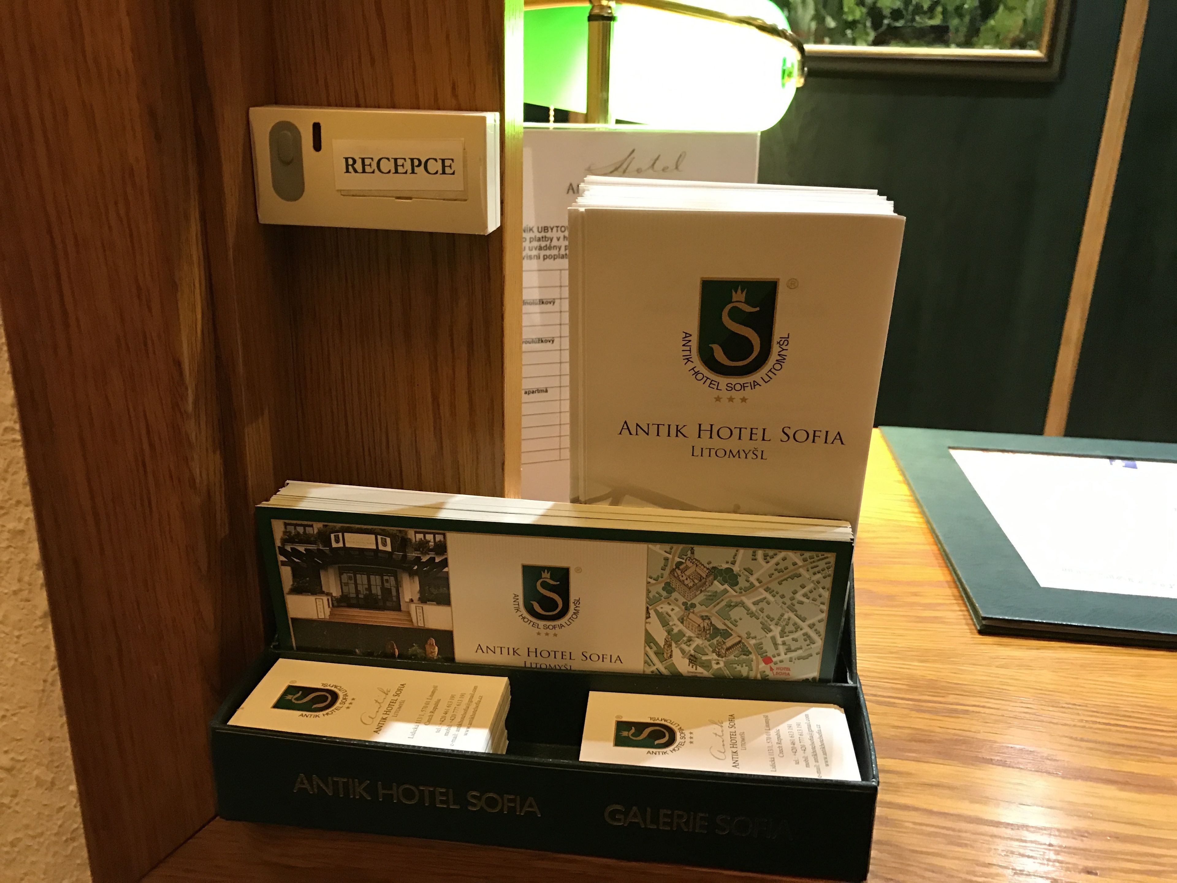 A reception desk with a sign labeled "RECEPTION" and a display of Antik Hotel Sofia brochures and a map.