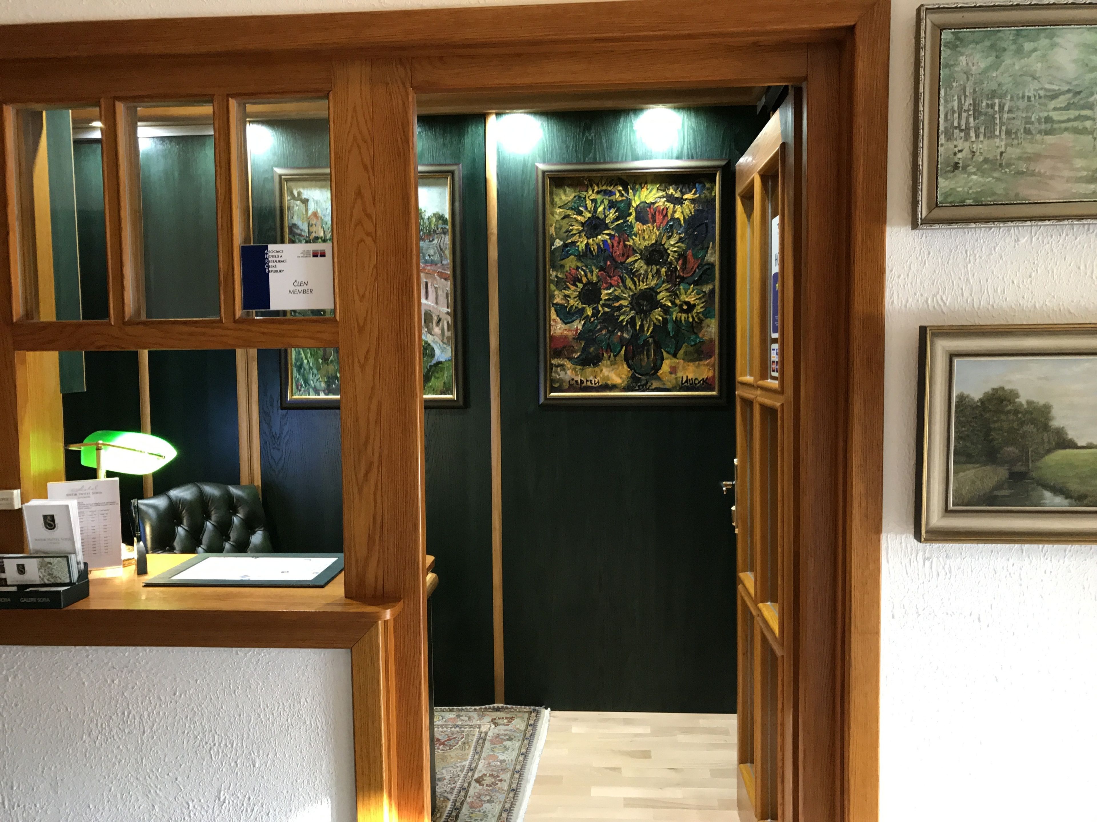 A reception area with a desk, chair, framed artwork, and a dark-colored wall.