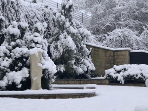 Ett snötäckt utomhusområde med en stenmur och ett staket av metall.