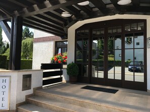 A hotel entrance with a covered porch, a sign reading "HOTEL", and a car parked outside.