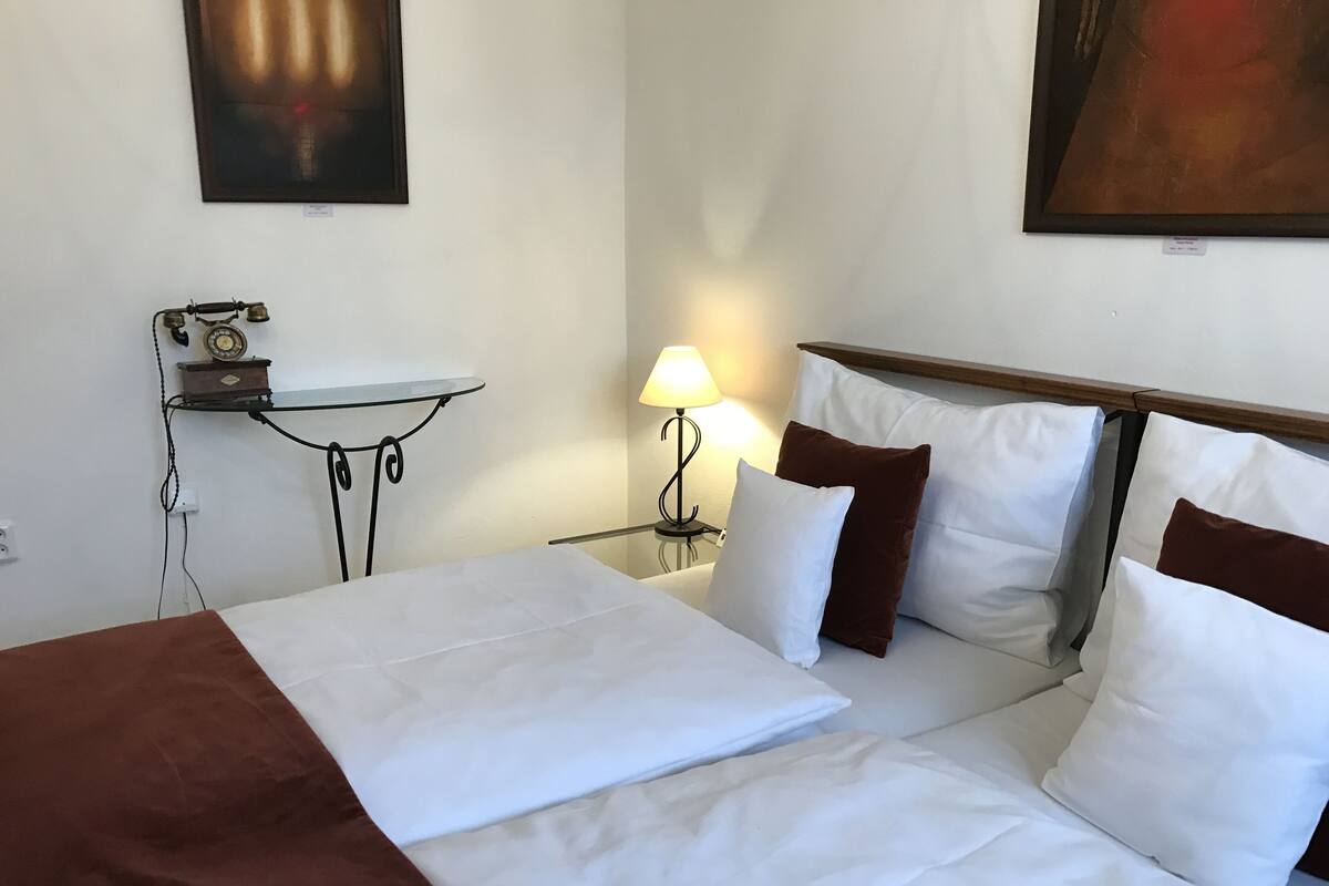 Ein Hotelzimmer mit Bett, einem kleinen Tisch mit Lampe und einem Bild an der Wand.