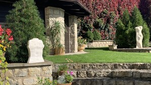 Un jardín ajardinado con estructuras de piedra, plantas en macetas y una variedad de flores.