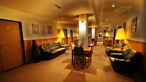 A hotel lobby with a leather sofa, a dining table with chairs, and a reception desk. - Hotel Bohemians (Prague)