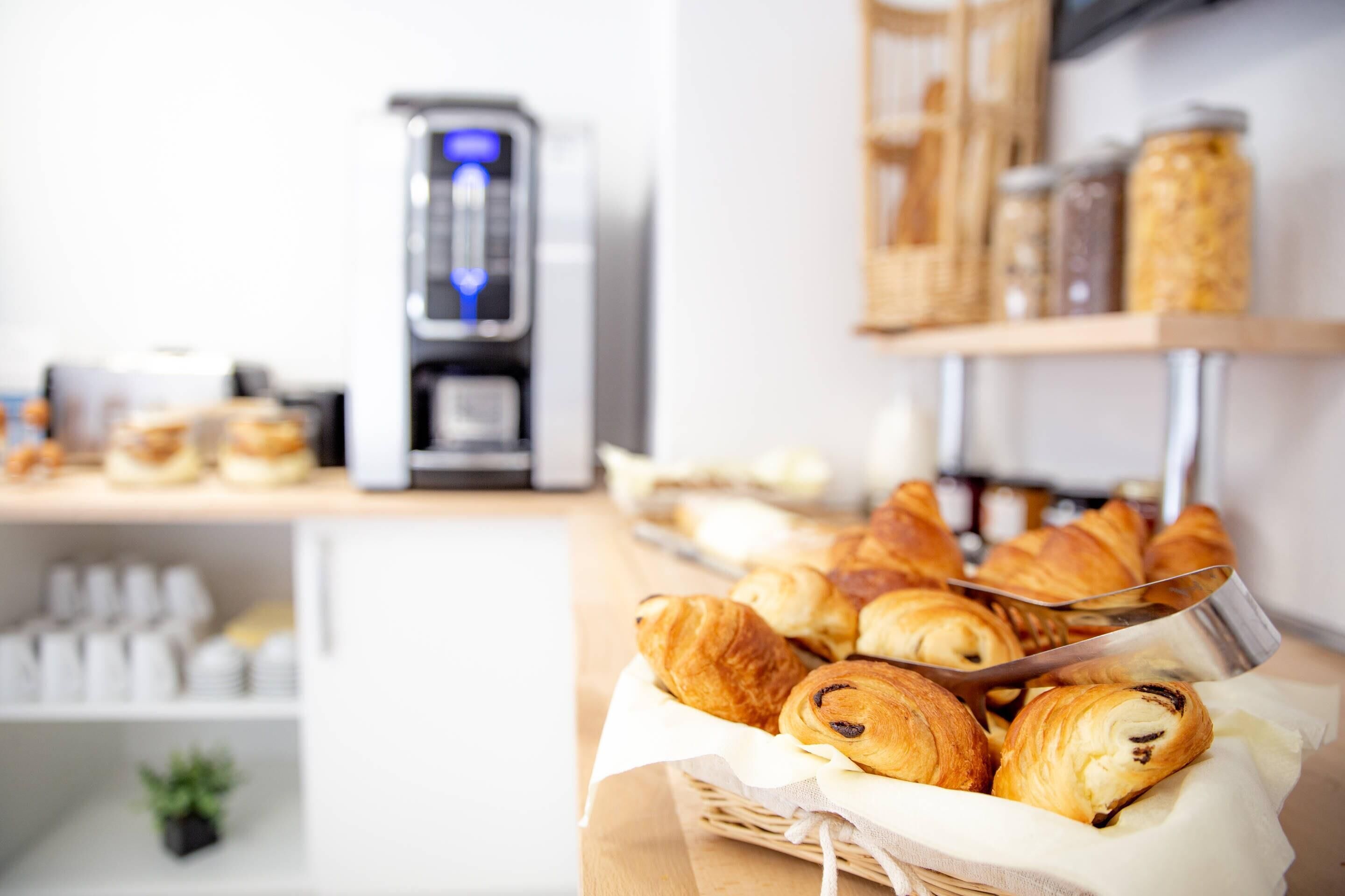 A bakery display with croissants and a coffee machine.