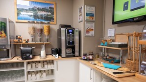Un área de cocina con cafetera, dispensador de agua y diferentes utensilios.