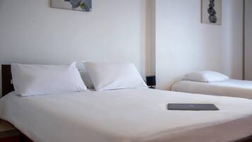 Een hotelkamer met twee bedden, witte beddengoed, een laptop op één bed en kunstwerken aan de muren.