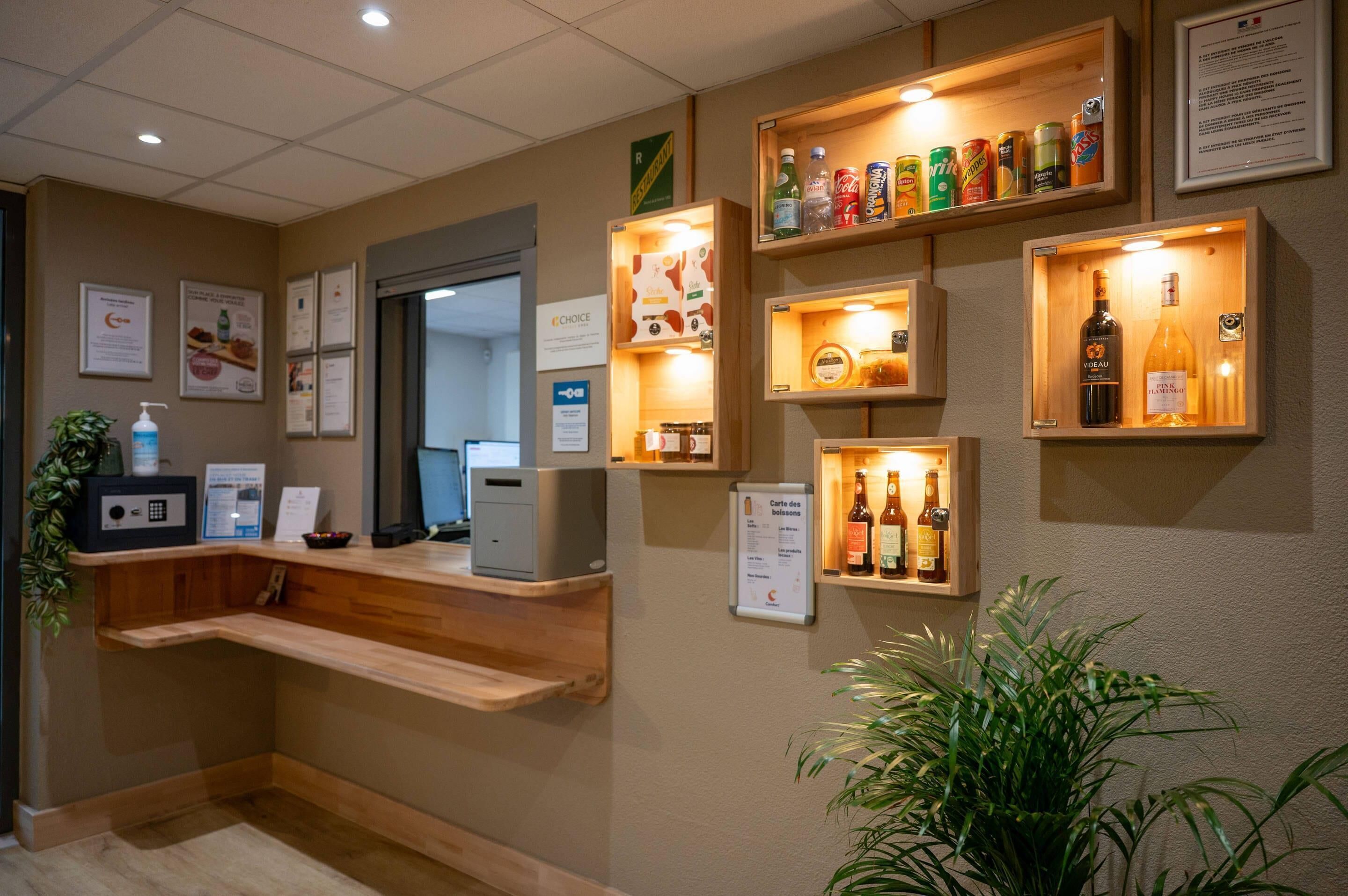 Un espace d’accueil avec des étagères en bois où sont exposées des boissons et une caisse enregistreuse.