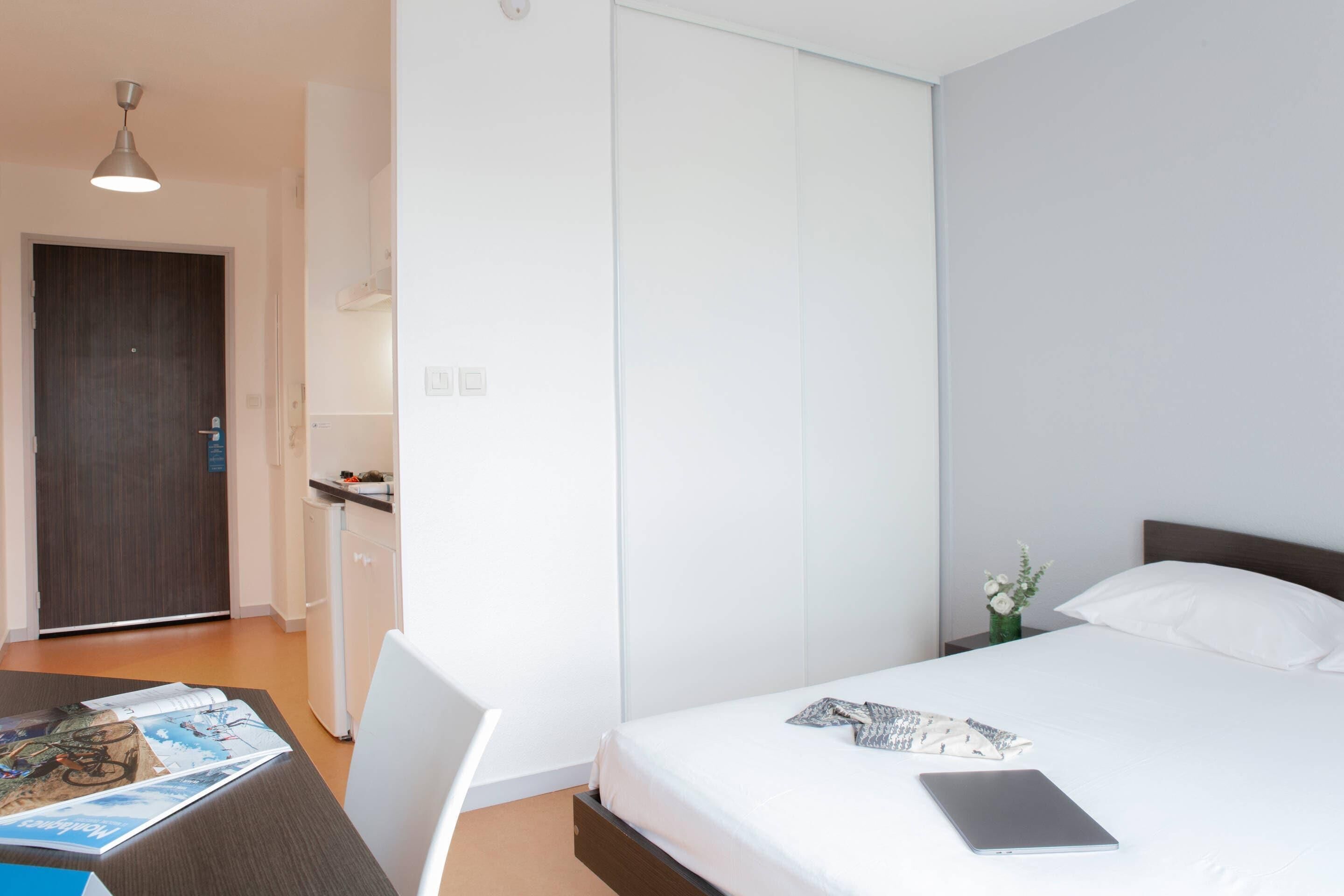 Habitación de hotel con cama, escritorio con silla, una mesita y un armario.