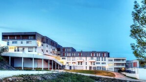 Un edificio residencial moderno de varios pisos con una mezcla de balcones y ventanas, que presenta una estructura curva en el lado izquierdo.