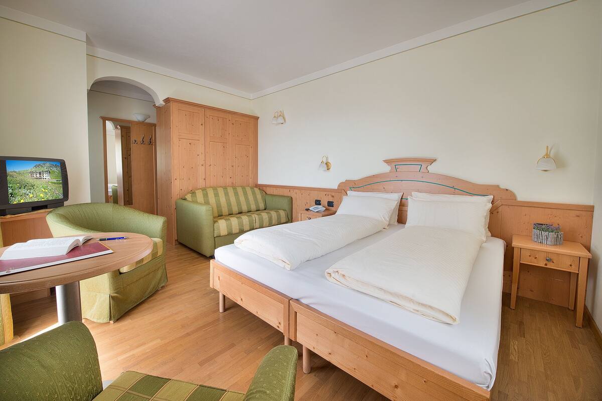 Una habitación de hotel con cama doble, un escritorio con silla, televisión y armario.