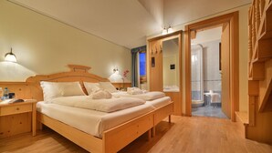 Een houten bed met twee kussens en een nachtkastje met een lamp.
