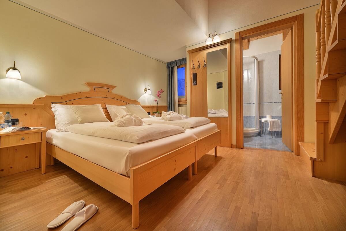 Una cama de madera con dos almohadas y una mesita de noche con una lámpara.