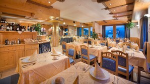 Een restaurant met houten inrichting, verschillende eettafels en stoelen.