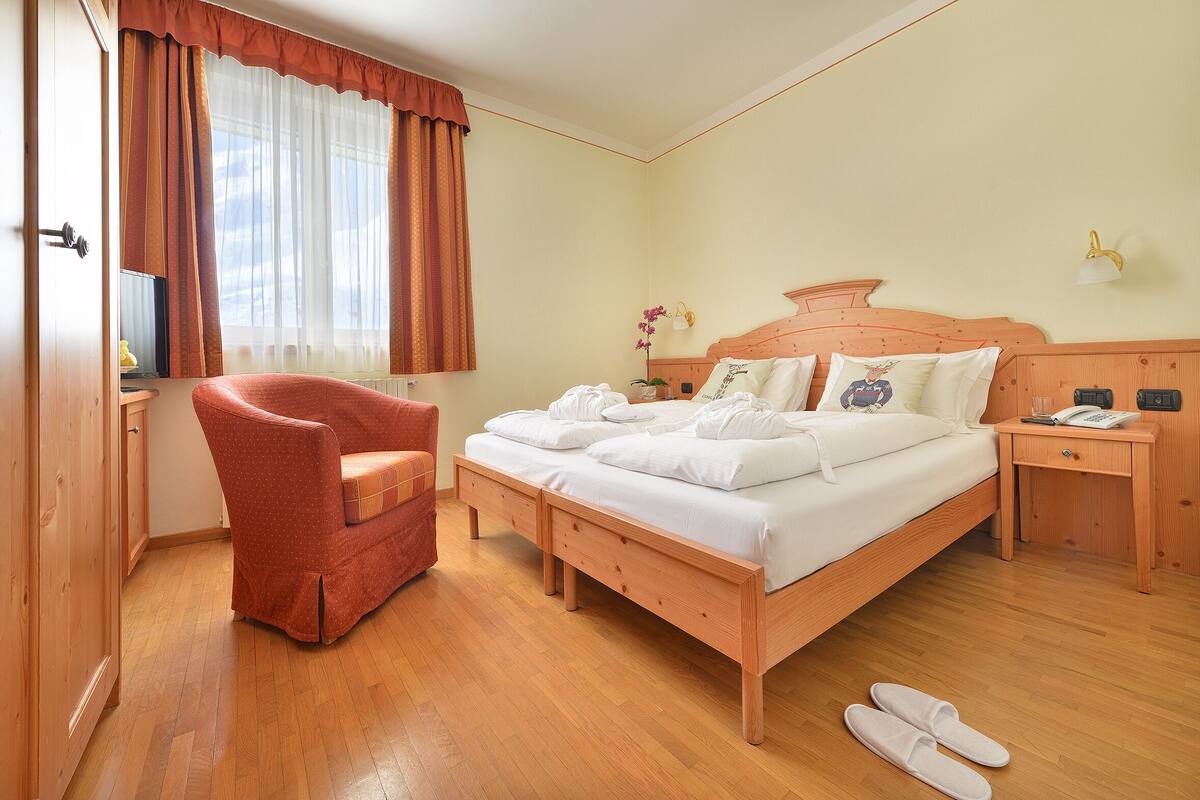 Un dormitorio ordenado con una cama de madera, un sillón rojo y una mesita de noche con una lámpara.