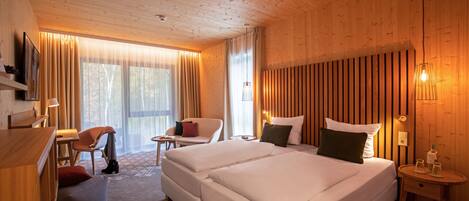 A hotel room with two beds, a desk, a chair, and a TV.