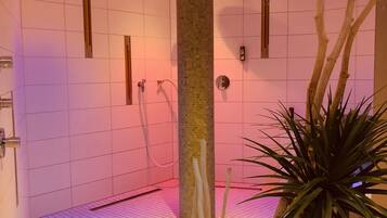 A spa room with a tiled floor, a central pillar, and a plant.