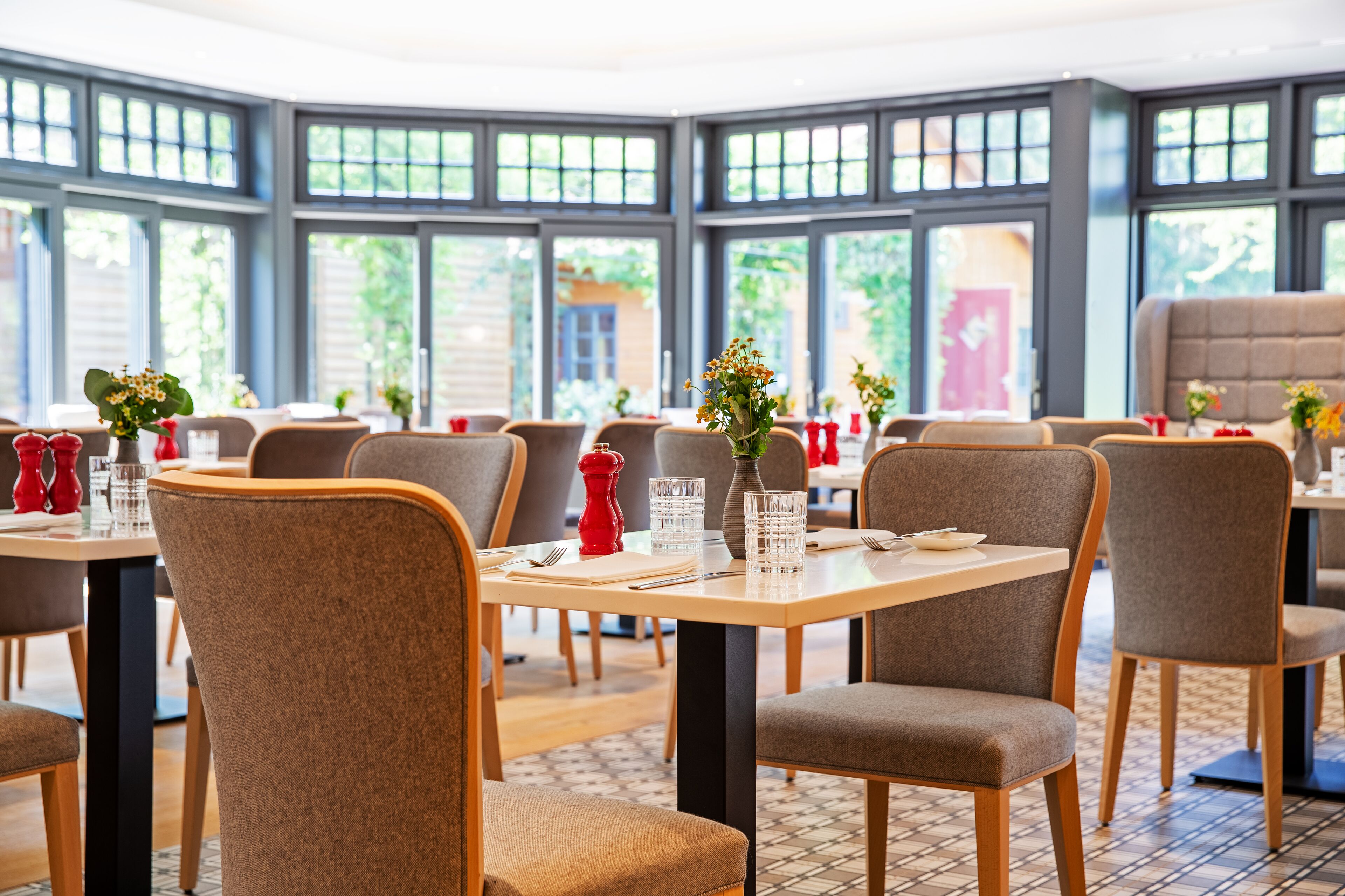 A restaurant with multiple tables, chairs, and large windows.