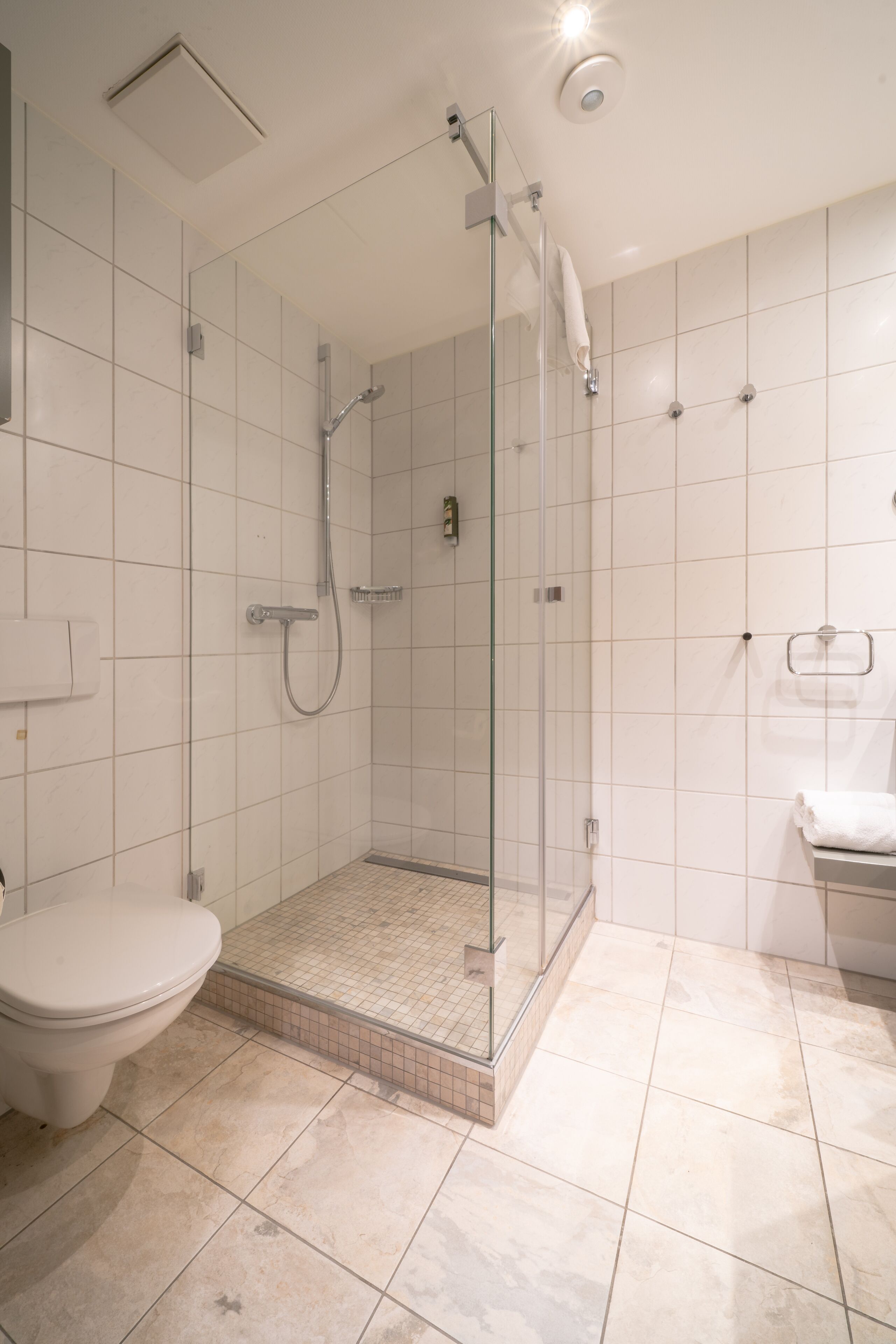 Un baño moderno con ducha de vidrio, inodoro y lavabo.