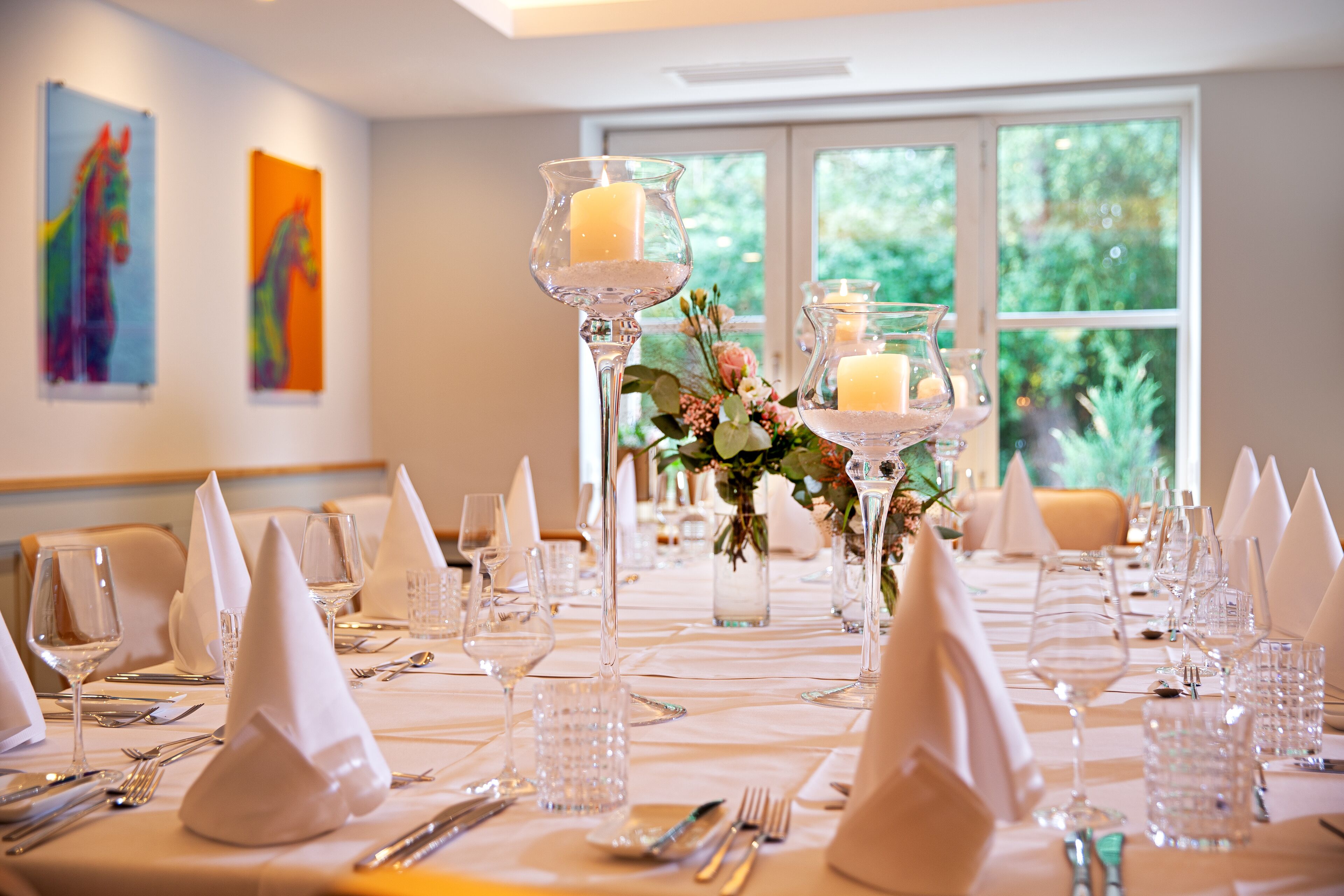 A table set for a formal event with clear glassware, white napkins, and candles.