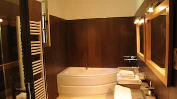 A modern bathroom with a large bathtub, a glass shower enclosure, and a wooden vanity with a mirror.