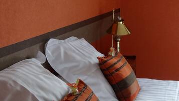 Una habitación de hotel con cama, almohadas, lámpara y obras de arte enmarcadas en las paredes.