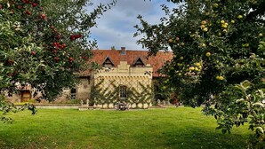 A traditional building with a tiled roof, surrounded by a well-maintained lawn and fruit-bearing trees.