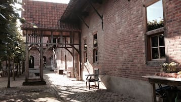 Une cour avec un bâtiment en briques, un chemin en pierre, des bancs en bois et un kiosque.