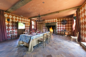Una sala menjador amb una taula gran preparada per a dinar, una llar de foc i un mur amb un disseny decoratiu.