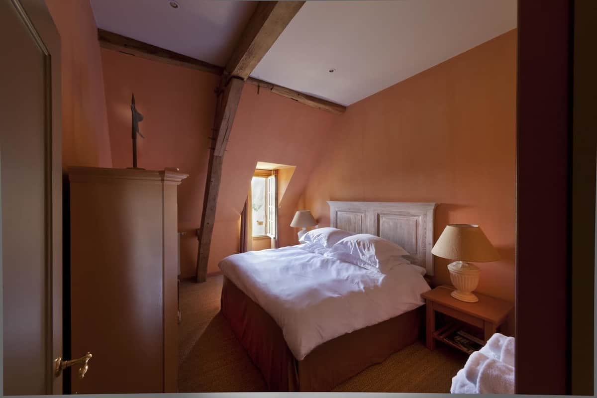 Une chambre à coucher avec un lit, des tables de chevet, une commode et une fenêtre.