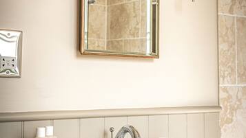 A bathroom with a large mirror, two wall-mounted lights, a sink, and toiletries.