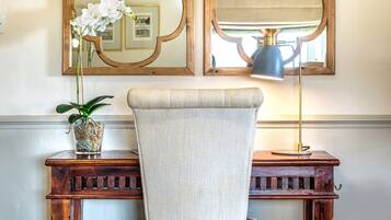 A wooden desk with a chair, a mirror, and a lamp.